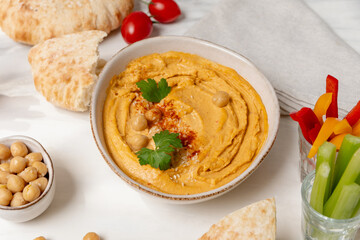 reamy hummus in a white bowl, garnished with chickpeas and herbs, paired with crispy flatbreads and olive oil, showcasing a vibrant and appetizing snack presentation