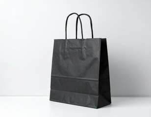 A sleek black shopping bag with sturdy handles rests on a clean white background, highlighting its minimalist design and versatility for various purchases.