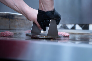 Chef pressing smash burger patties on a hot grill