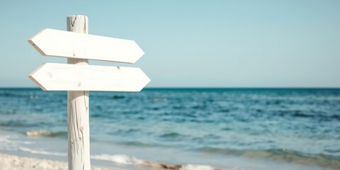 Blank white wooden directional signpost on a sandy beach with ocean waves in the background