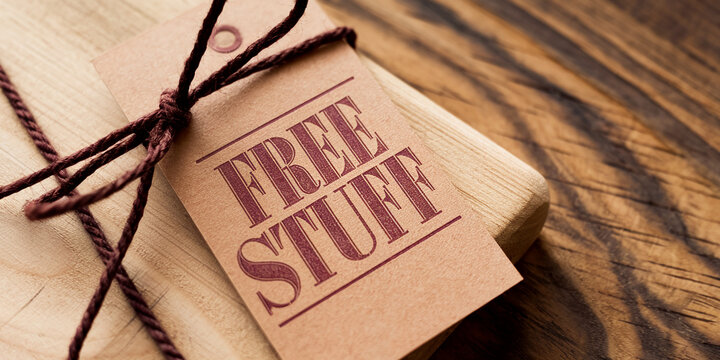 Close-up of a wooden gift tied with twine and a tag reading "Free Stuff", suggesting a giveaway or promotional offer, symbolizing generosity and opportunity
