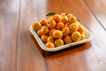 Stack of Mandarin oranges in a square tray on a wooden table