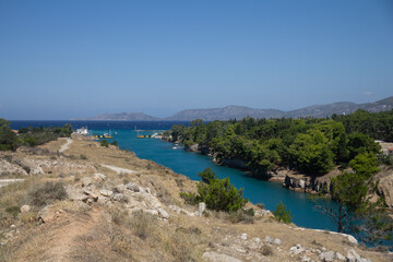 A scenic view looking across the Corinth Canal from one of its banks, capturing the steep cliffs and turquoise water below. A peaceful moment near one of Greece’s most famous man-made structures.