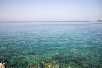 Capture the crystal-clear waters of Loutraki's beach, showcasing the transparency and vibrant blue hues of the sea.