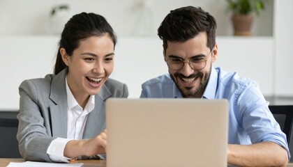 Happy colleagues celebrating success while working on a laptop in a modern office environment with natural lighting
