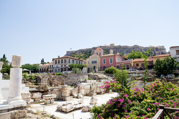 Naklejka premium A bright and colorful photo taken in Athens, Greece, showing blooming flowers in the foreground with ancient ruins in the background. The image captures a relaxed, sunny holiday atmosphere blending hi