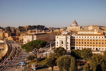 Obraz premium A sweeping view over Vatican City and St. Peters Basilica from Castel Sant Angelo, capturing the layout of Via della Conciliazione flanked by historic buildings and Roman pines