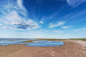 Obraz premium The pools and wet sand of the Headwell Sands at Tentsmuir Point as the Tide goes out under a dramatic sky in May.
