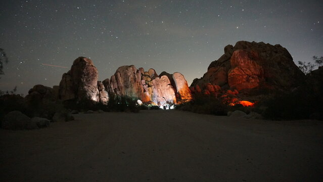 Large boulders lit up with lights from campsites under clear night sky