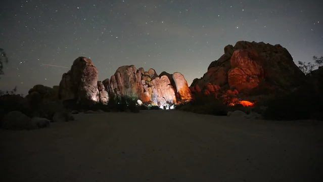 Large boulders lit up with lights from campsites under clear night sky