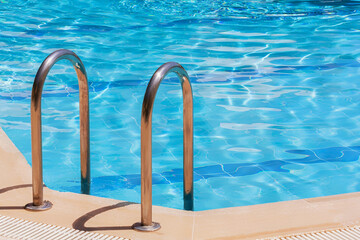 Fototapeta premium Outdoor swimming pool with clear blue water and stainless steel ladder, perfect for summer vacation and relaxation concepts