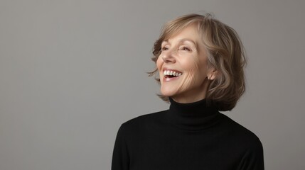A profile view of an older woman with silver hair styled in a bun, wearing a black turtleneck.