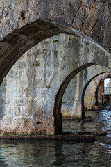 Interior of Alanya ancient shipyard Tersane with stone arches and reflective water. Turkey (Turkiye)