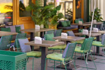 Outdoor cafe with lots of plants. Outdoor tables and chairs in a restaurant.
