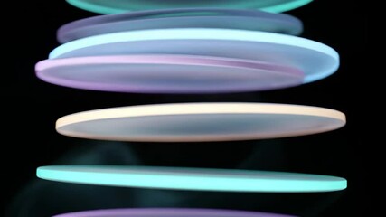 floating glass discs rotate in sync as light pulses cascade down in a softly lit atmospheric void - Powered by Adobe