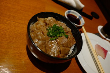 Delicious Japanese Beef Bowl with Tender Meat, Rice and Garnish Served in a Traditional Black Bowl
