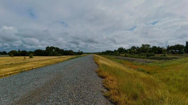 Time-lapse footage of the dense clouds rolling over a narrow rural road during daytime