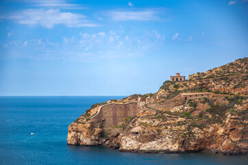 Beautiful view of the ocean with a rocky shoreline. The water is calm and the sky is clear.