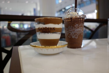 Delicious layered dessert in a stylish cup beside a refreshing chocolate beverage on a chic café table
