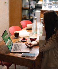 woman working on laptop in cozy cafe with coffee and dessert