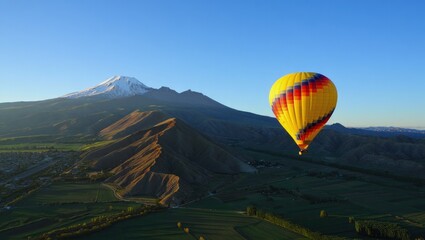 Naklejka premium Yellow Hot Air Balloon Soaring Over Autumnal Mountain Landscape at Sunrise
