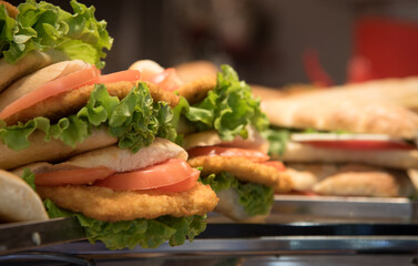 Delicious chicken sandwiches with lettuce and tomato filling a display case
