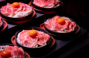Sukiyaki or yakiniku, japanese style raw beef with egg yolk and onion being cooked on a hot plate