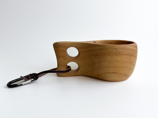 Top view of wooden Kuksa cup with a leather strap and carabiner.  Traditional Nordic style mug for outdoor adventures and camping.   Handcrafted wooden drinking vessel on a white background.