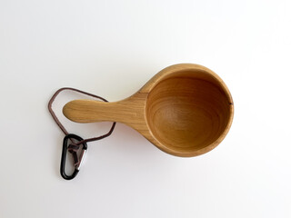 Side view of wooden Kuksa cup with a leather strap and carabiner.  Traditional Nordic style mug for outdoor adventures and camping.   Handcrafted wooden drinking vessel on a white background.