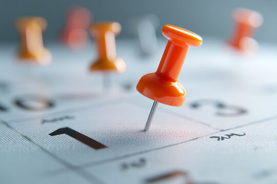 Close-up of orange pin on calendar, highlighting date one, suggesting planning, scheduling, or reminder concept