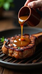 Grilled steak is being topped with rich brown sauce poured from a small jug, creating a savory and appetizing presentation
