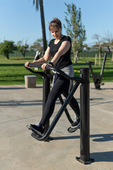 Obraz premium Mature woman using outdoor fitness equipment on a sunny day