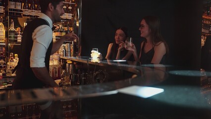 Portrait of VIP guest in beautiful woman making a toast in cheers at luxurious nightclub at vibrant nightlife party. Sitting at counter bar talking with barman atmosphere party lifestyle. Vinosity.
