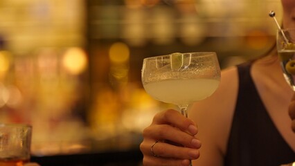 Closeup group friends making a toast with cocktail martini, margarita, paloma, old fashioned at luxurious bar, lively conversation drinks celebrating a special party at vibrant nightclub. Vinosity.