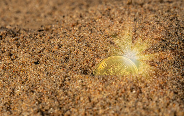 A gold coin in the sand.Search for lost jewelry on the beach.