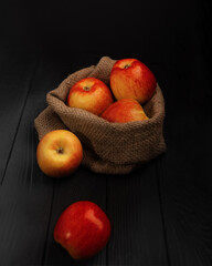 five red apples in a bag on a black background