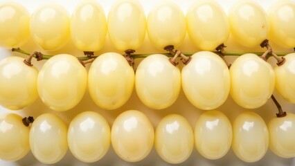 Clusters of smooth yellow grapes are closely arranged, displaying their plump and fresh appearance on a white background