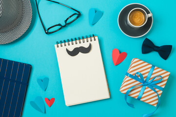 Happy Father's day concept with notebook, coffee cup and gift box on blue background. Top view, flat lay