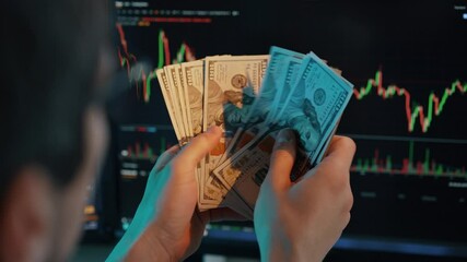 Trader Counting Dollars in Front of Charts - Powered by Adobe