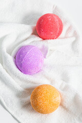 Colorful bath bombs rest on a soft white towel ready for relaxation time