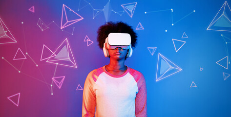 African girl with VR glasses standing at blue and pink background and looking at floating geometric...