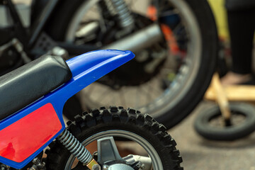 Small motorcycle on display with blurred background showing larger motorcycle