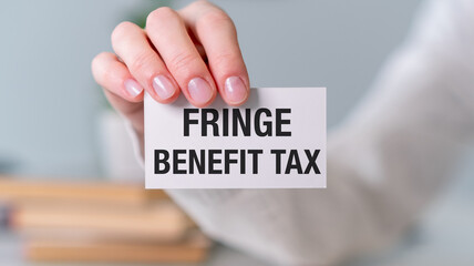 A person is holding a white card that says Fringe Benefit Tax