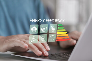 Energy efficiency concept. Energy efficient house building rate label audit. Person using laptop with energy efficiency rating icon on virtual screen.