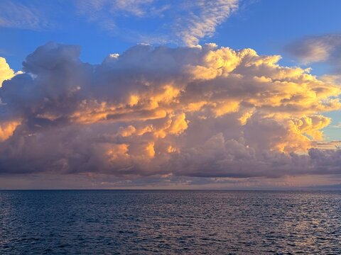 Dramatic sunrise clouds over calm ocean.