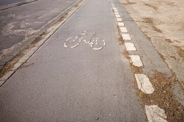 Fototapeta premium Bike lane symbol showing through cracked asphalt on city street