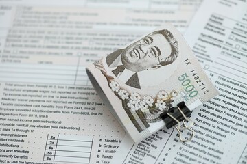 North Korean won money bills in big amount lies on table with tax forms close up