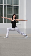 A woman performs a warrior yoga pose outdoors, exuding balance and strength. This image embodies...