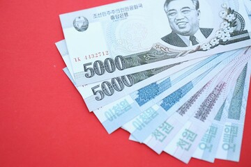 North Korean won money bills in big amount lies on red color table close up