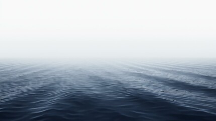 Obraz premium The tranquil sea stretches towards a hazy horizon, its surface gently rippling with subtle waves under a soft, diffused light in this serene seascape image.
